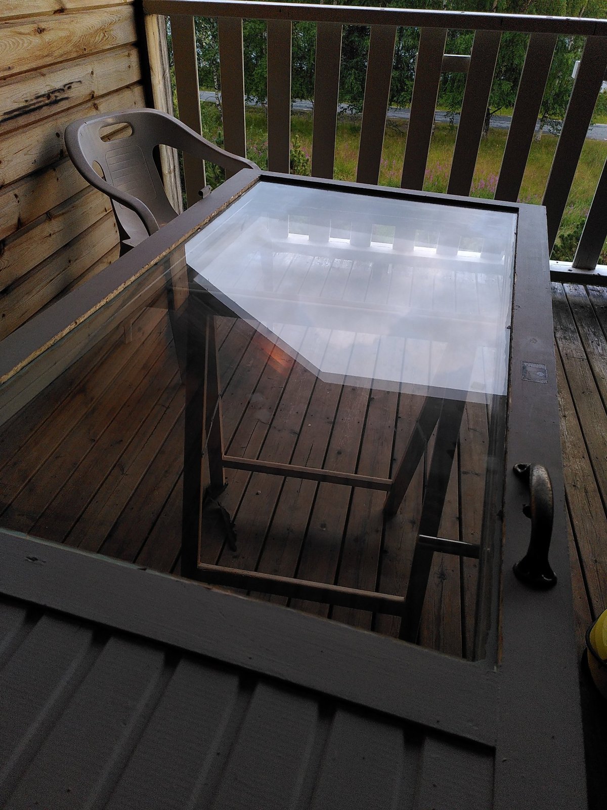 Ausgehängte gekoppelte Verandatür mit neuer Scheibe auf der Veranda eines Holzhauses in Västerbotten