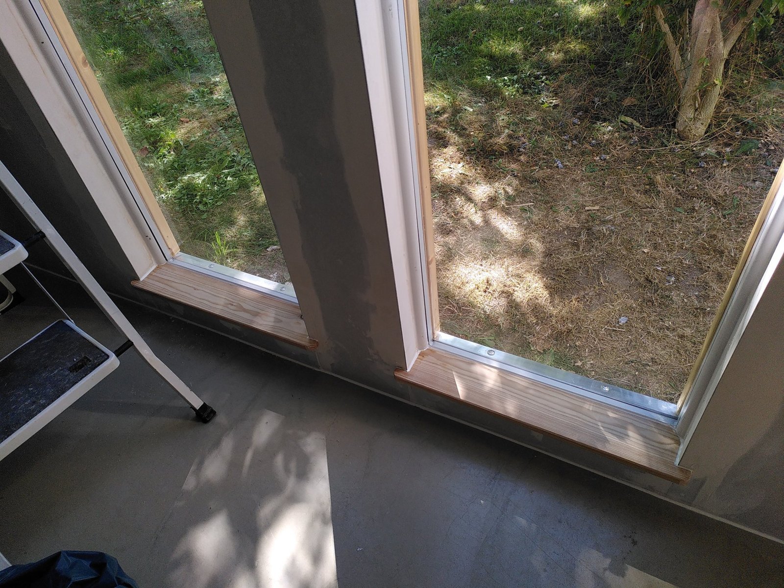 Eingebaute schmale Fenster mit Fensterbänken aus Holz, Innenwand gespachtelt