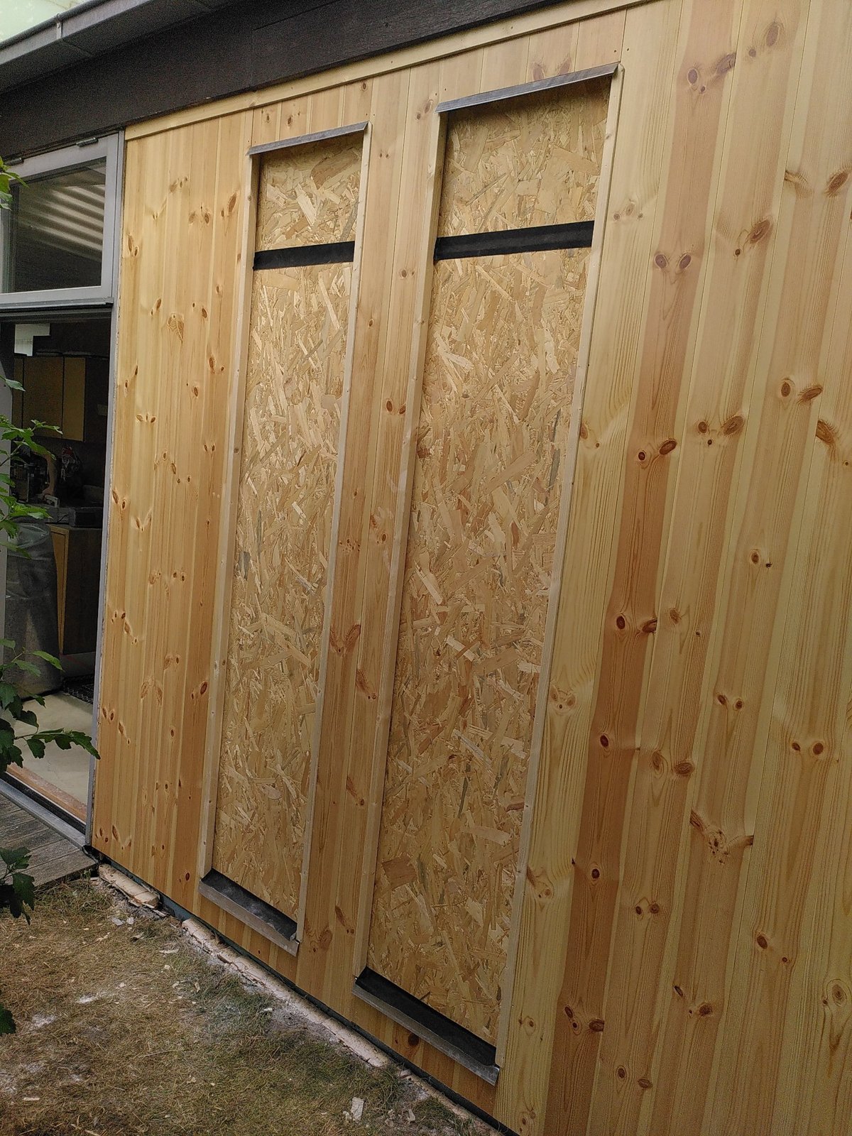 Außenverkleidung aus Profilbrettern, Fensteröffnungen noch mit OSB verschlossen