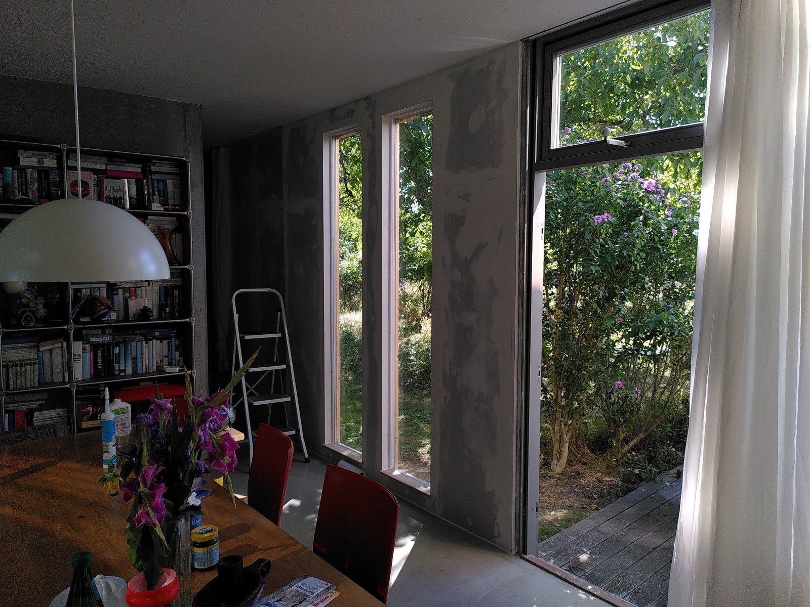 Wohnraum mit neuer, gespachtelter Wand und zwei schmalen Fenstern zum Garten