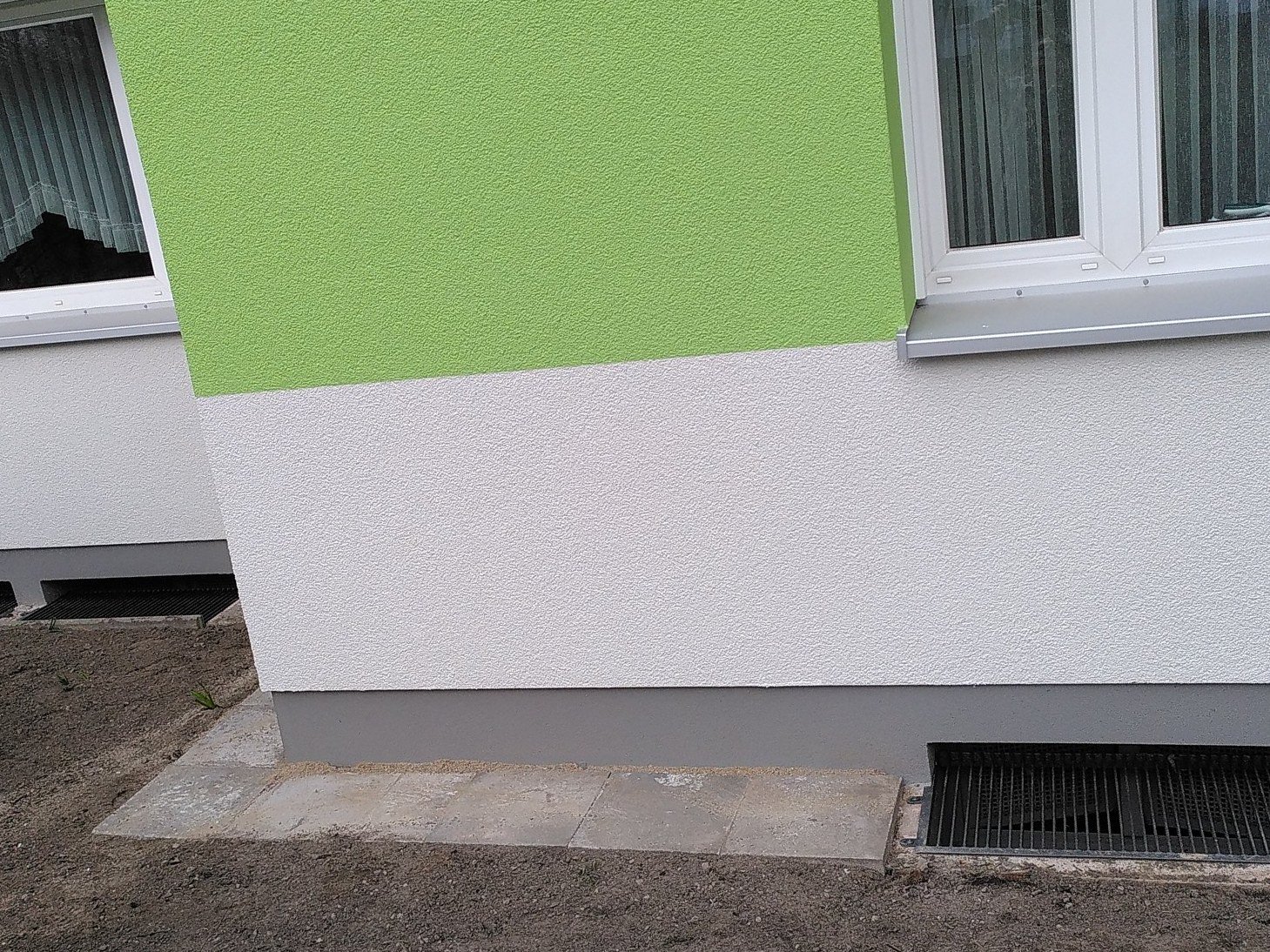 Tilläggsisolerad fasad på ett flerbostadshus med anpassat ljusschaktsgaller i sockeln