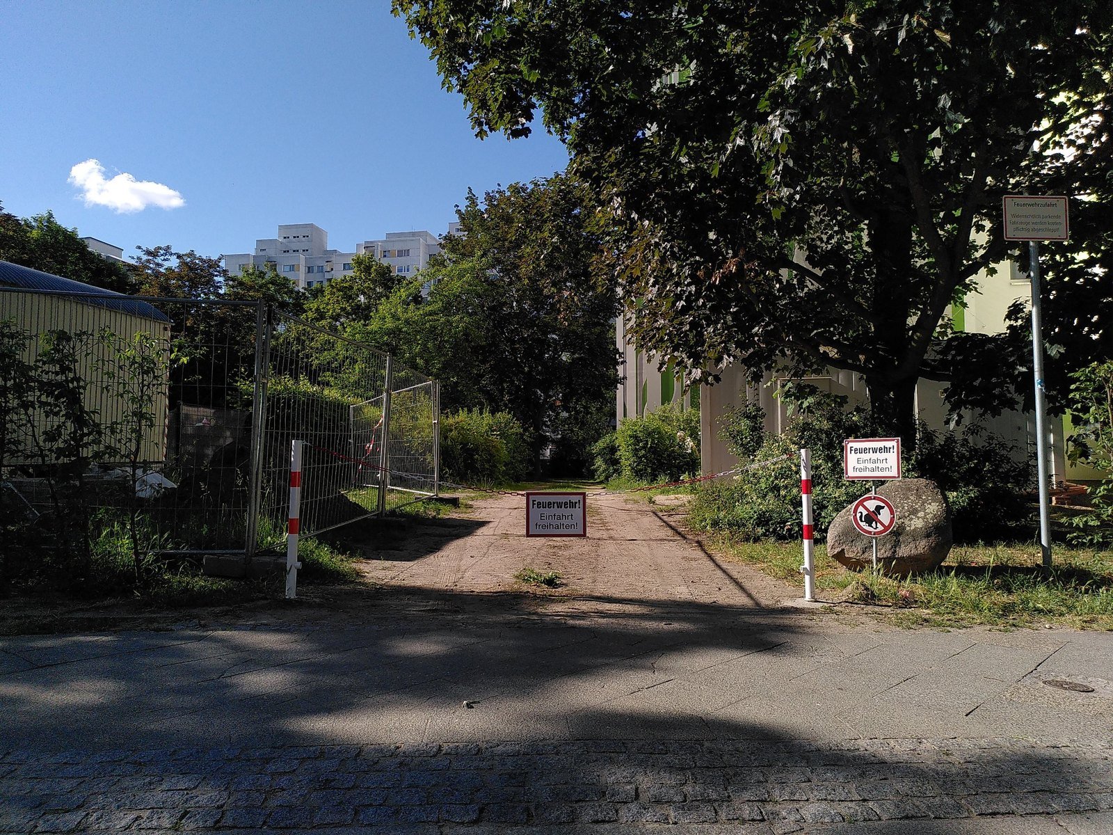 Two red-and-white removable bollards with triangular locks and fire department access sign in front of the driveway